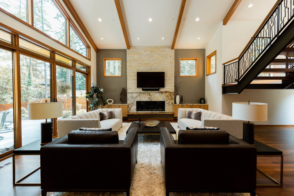 Offenes Modernes Wohnzimmer mit Kaminumrandung aus Stein, TV-Wand, grauer Wandfarbe, braunem Holzboden und Gaskamin in Seattle