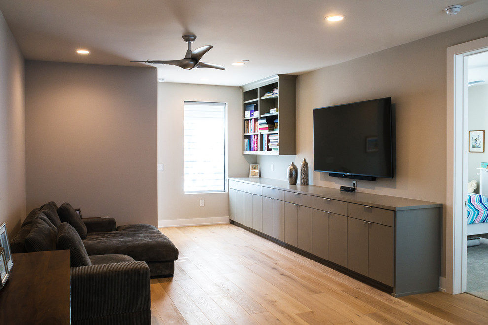 Ejemplo de sala de estar abierta contemporánea sin chimenea con paredes beige, suelo de madera clara y televisor colgado en la pared