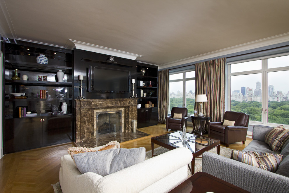 На фото: гостиная комната в классическом стиле с серыми стенами, паркетным полом среднего тона, стандартным камином, фасадом камина из камня и телевизором на стене