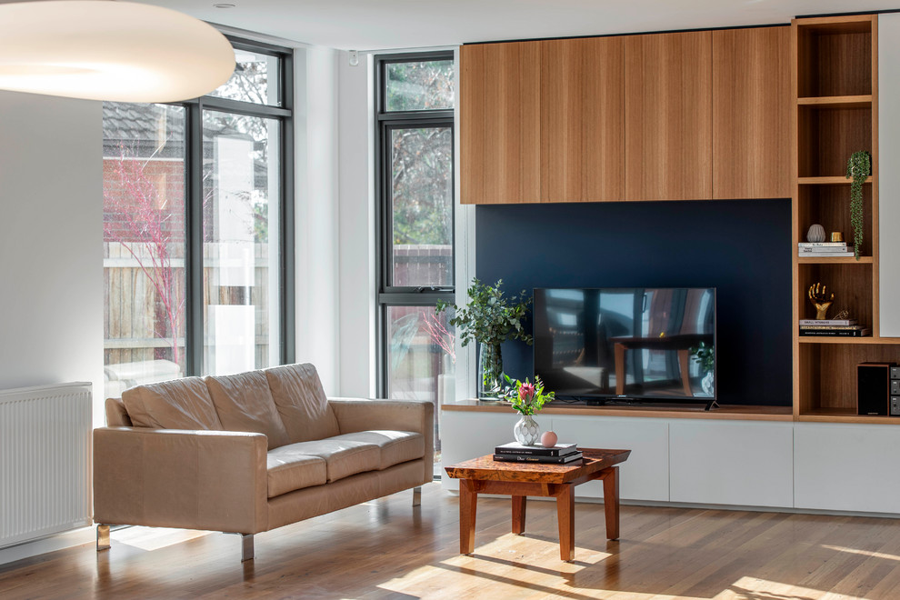 Modernes Wohnzimmer mit weißer Wandfarbe, hellem Holzboden und freistehendem TV in Canberra - Queanbeyan