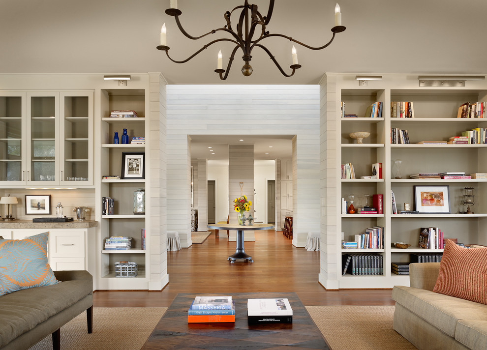Exemple d'une grande salle de séjour tendance avec un mur beige, un sol en bois brun et une bibliothèque ou un coin lecture.