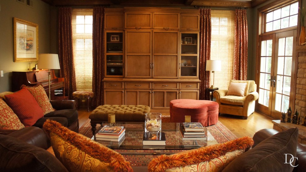 Foto de sala de estar abierta tradicional grande con paredes verdes, suelo de madera en tonos medios, todas las chimeneas, marco de chimenea de piedra, televisor retractable y suelo marrón