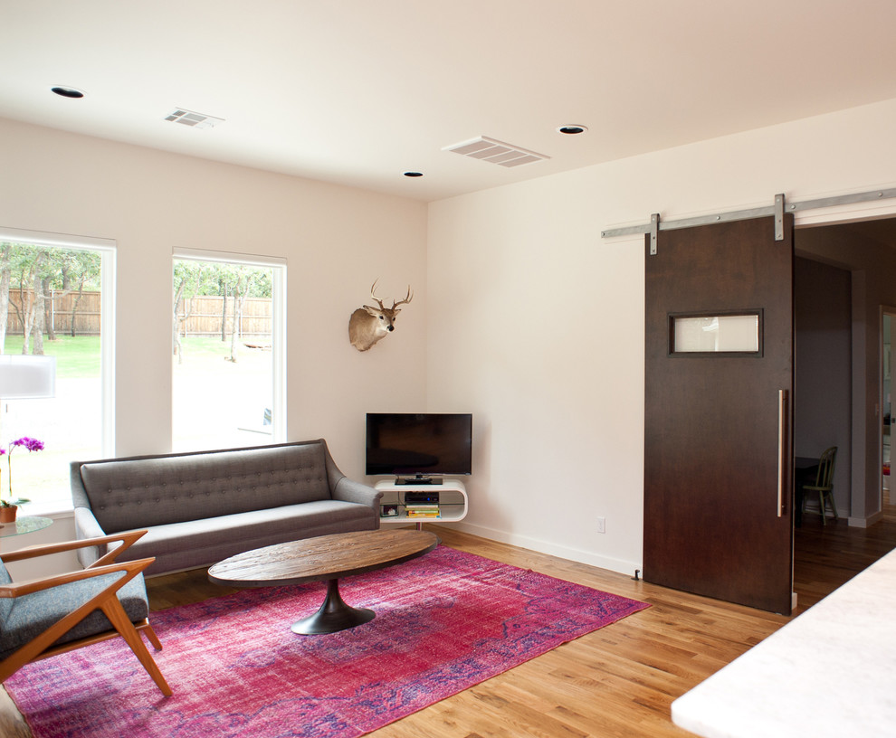 Стильный дизайн: гостиная комната среднего размера в современном стиле с белыми стенами, светлым паркетным полом, горизонтальным камином, фасадом камина из кирпича и телевизором на стене - последний тренд
