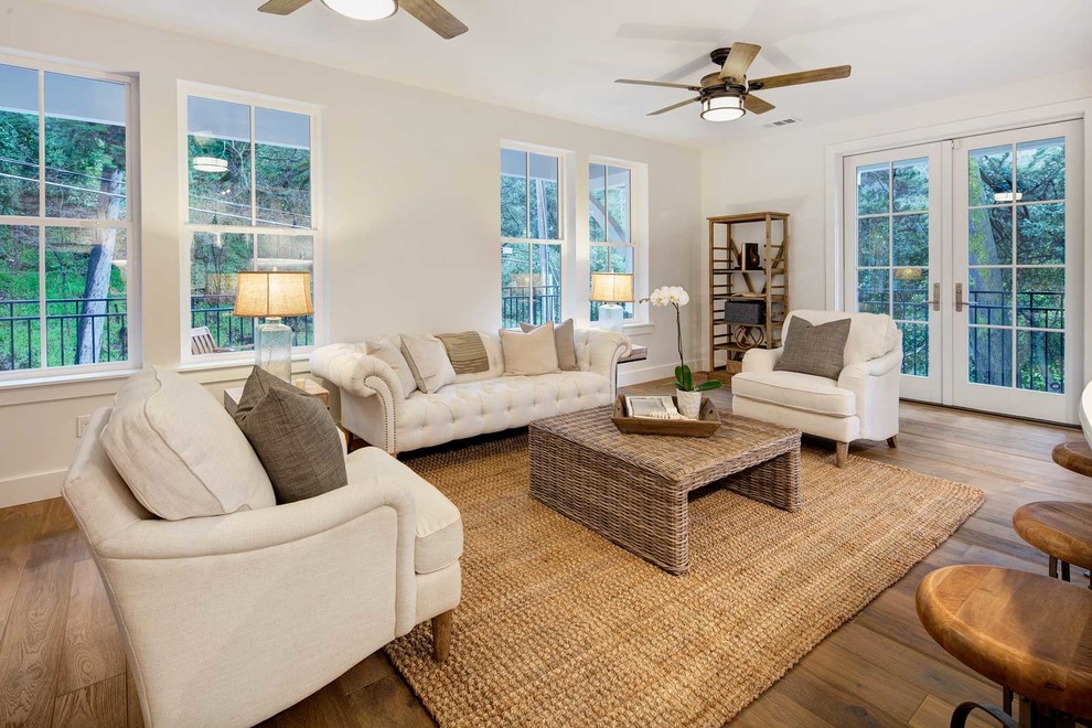 Modelo de sala de estar abierta campestre de tamaño medio con paredes blancas, suelo de madera en tonos medios y suelo marrón