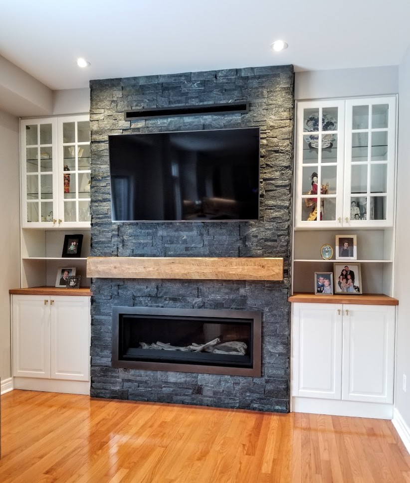Inspiration for a mid-sized transitional open concept light wood floor and orange floor family room remodel in Toronto with gray walls, a standard fireplace, a stone fireplace and a media wall
