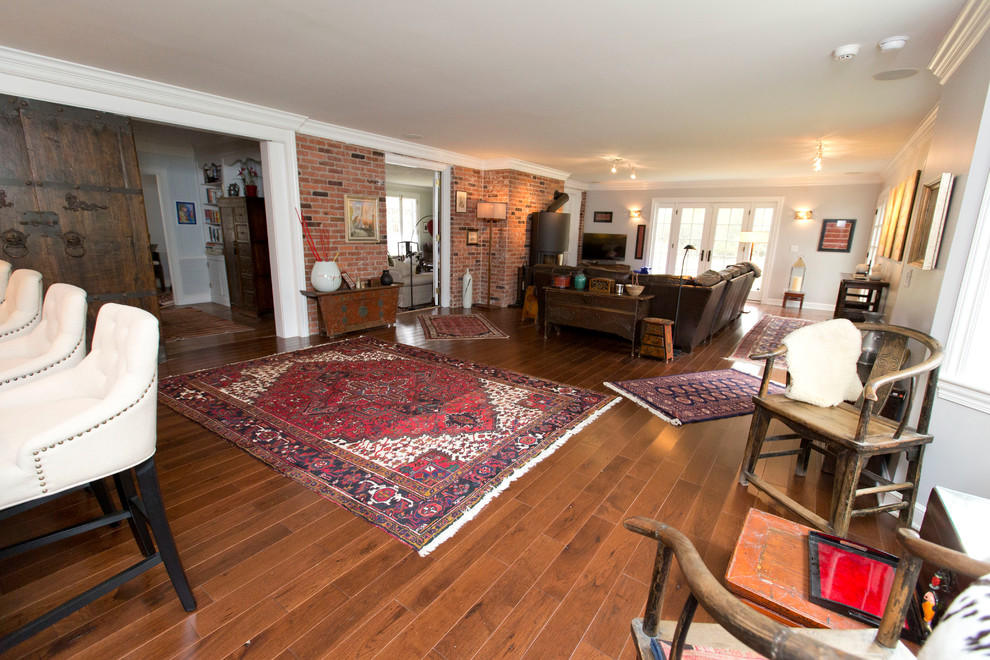 This is an example of a medium sized classic open plan games room in Cleveland with grey walls, a freestanding tv, dark hardwood flooring, a wood burning stove, a metal fireplace surround and brown floors.
