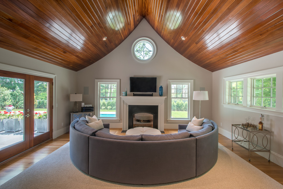 Ejemplo de sala de estar tradicional con paredes beige, televisor colgado en la pared, suelo de madera en tonos medios y todas las chimeneas