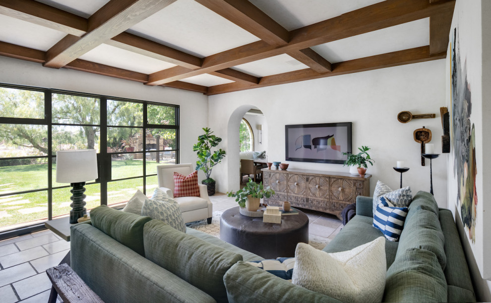 Modelo de sala de estar abierta mediterránea de tamaño medio sin chimenea con paredes blancas, suelo de travertino y suelo beige