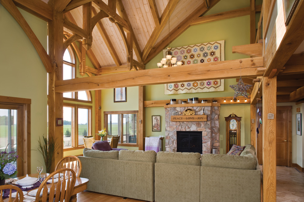 Offenes Country Wohnzimmer mit grüner Wandfarbe, Kamin, Kaminumrandung aus Stein und hellem Holzboden in Sonstige