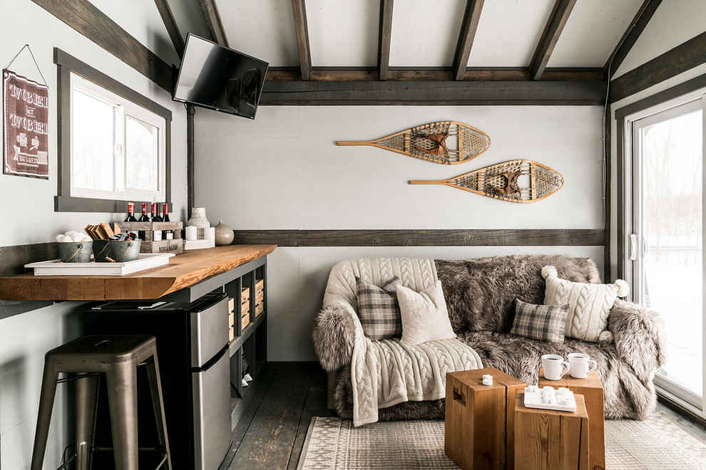 Ejemplo de sala de estar con barra de bar rural con paredes blancas, suelo de madera pintada, televisor colgado en la pared y suelo gris