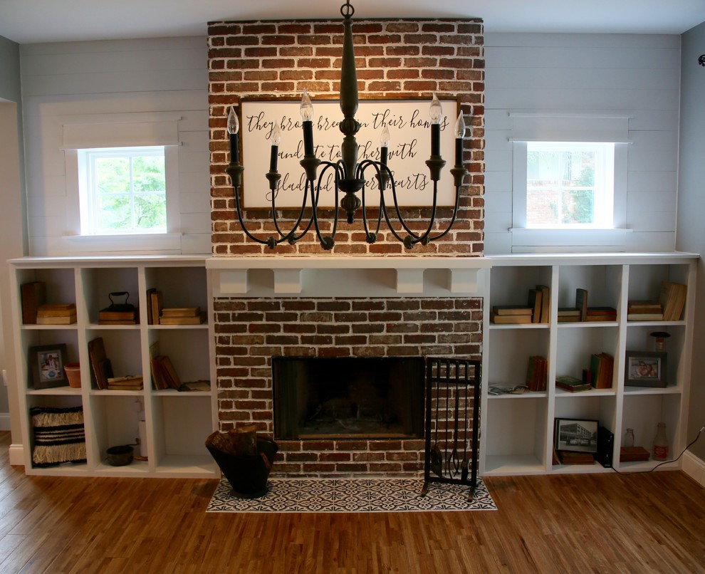 Ejemplo de sala de estar abierta de estilo americano pequeña con paredes blancas, suelo de madera en tonos medios, todas las chimeneas, marco de chimenea de ladrillo y suelo marrón
