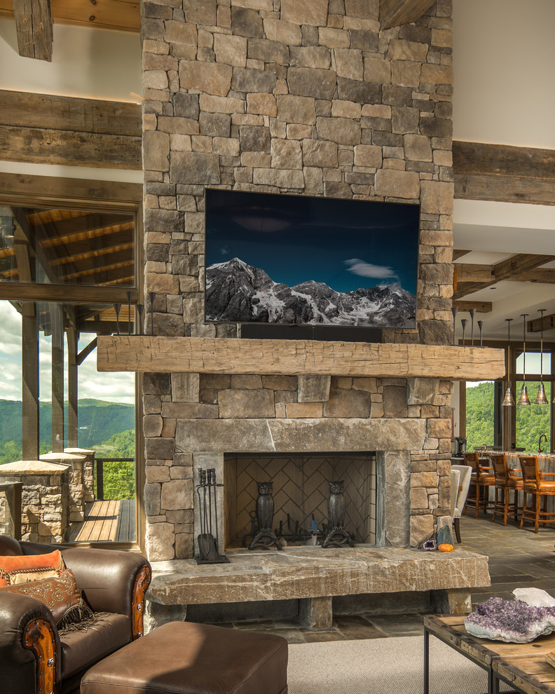 Inspiration for an expansive rustic open plan games room in Charlotte with beige walls, a standard fireplace, a stone fireplace surround and a wall mounted tv.