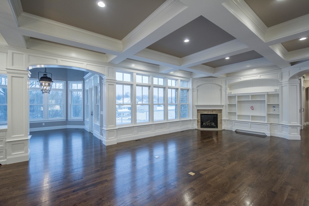 Inspiration for a large traditional open plan games room in Columbus with white walls, dark hardwood flooring, a corner fireplace, a stone fireplace surround, a wall mounted tv and brown floors.
