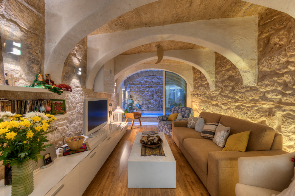 Abgetrenntes Rustikales Wohnzimmer mit beiger Wandfarbe, braunem Holzboden und freistehendem TV in Sonstige