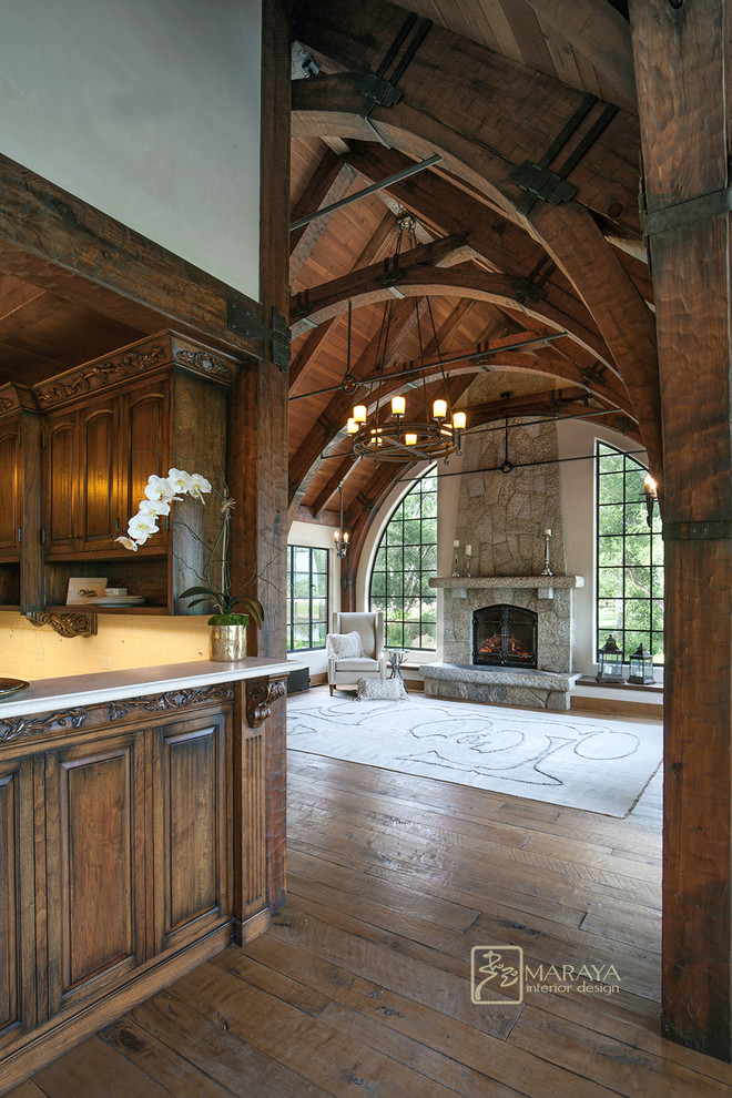 Imagen de sala de estar abierta campestre de tamaño medio con suelo de madera en tonos medios, todas las chimeneas y marco de chimenea de piedra