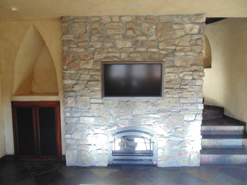 На фото: открытая гостиная комната в современном стиле с бежевыми стенами, полом из сланца, стандартным камином, фасадом камина из камня и мультимедийным центром