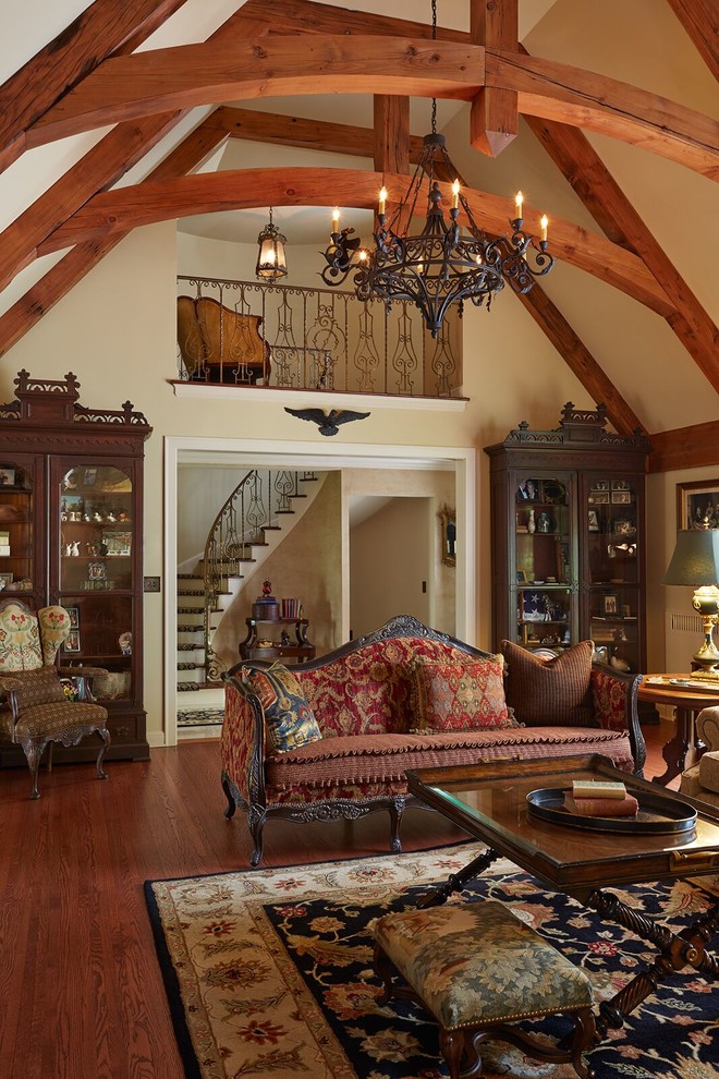 Modelo de sala de estar tradicional con paredes beige, suelo de madera en tonos medios, todas las chimeneas y marco de chimenea de piedra
