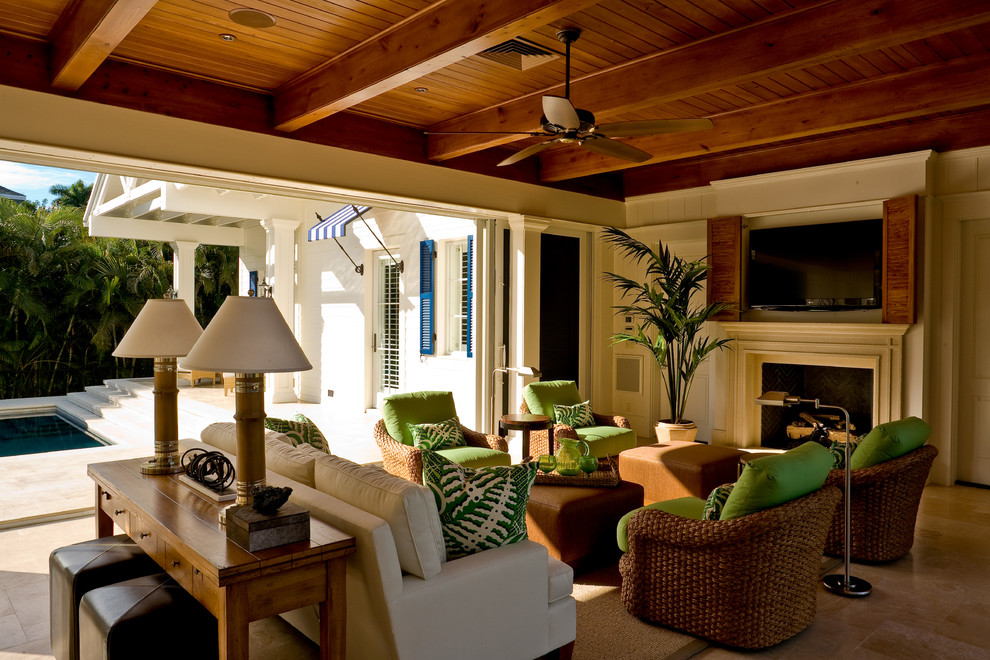 マイアミにある高級な中くらいなトロピカルスタイルのおしゃれなオープンリビング (白い壁、ライムストーンの床、標準型暖炉、木材の暖炉まわり、壁掛け型テレビ) の写真