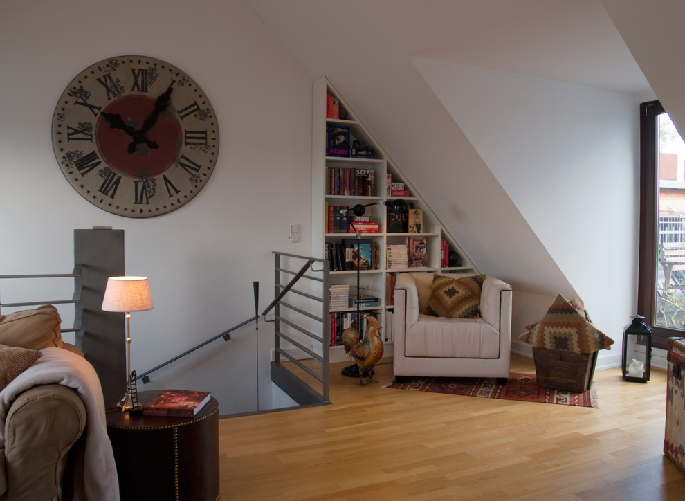 Immagine di un soggiorno eclettico stile loft con libreria, pareti bianche e parquet chiaro