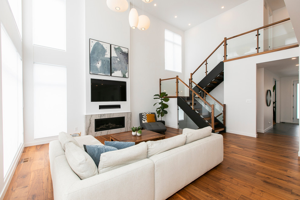 Großes, Offenes Modernes Wohnzimmer mit weißer Wandfarbe, braunem Holzboden, Kamin, Kaminumrandung aus Stein, Multimediawand und braunem Boden in Ottawa