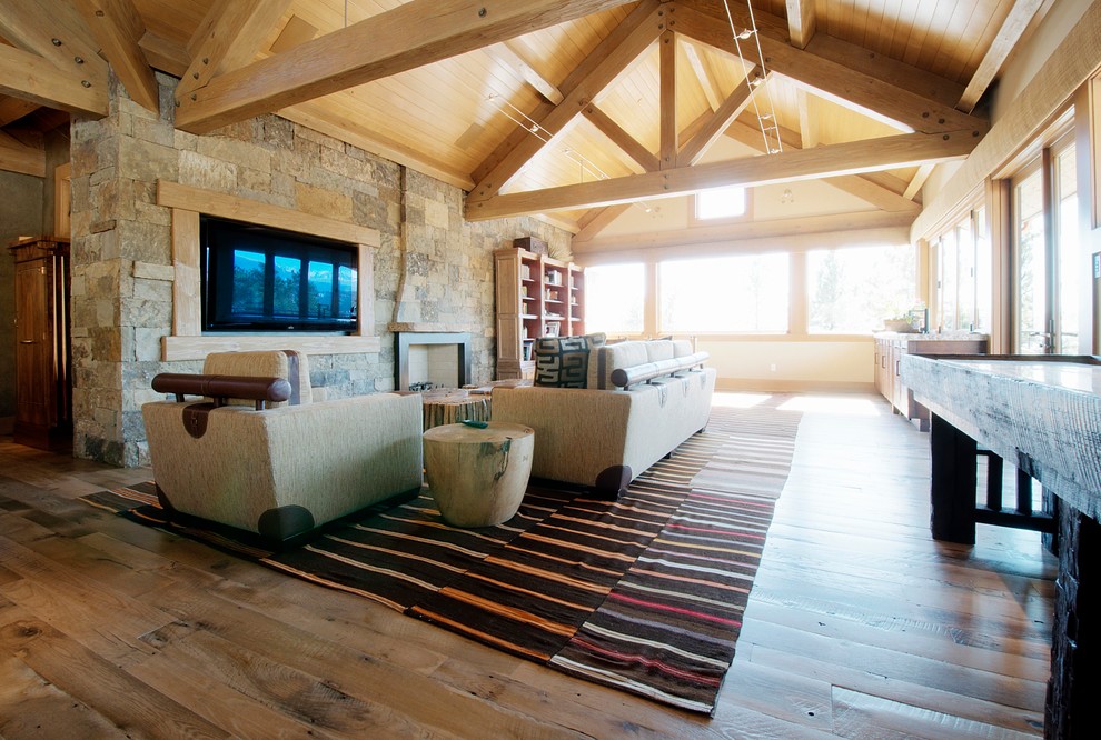 Exemple d'une salle de séjour montagne ouverte avec un sol en bois brun et un manteau de cheminée en pierre.