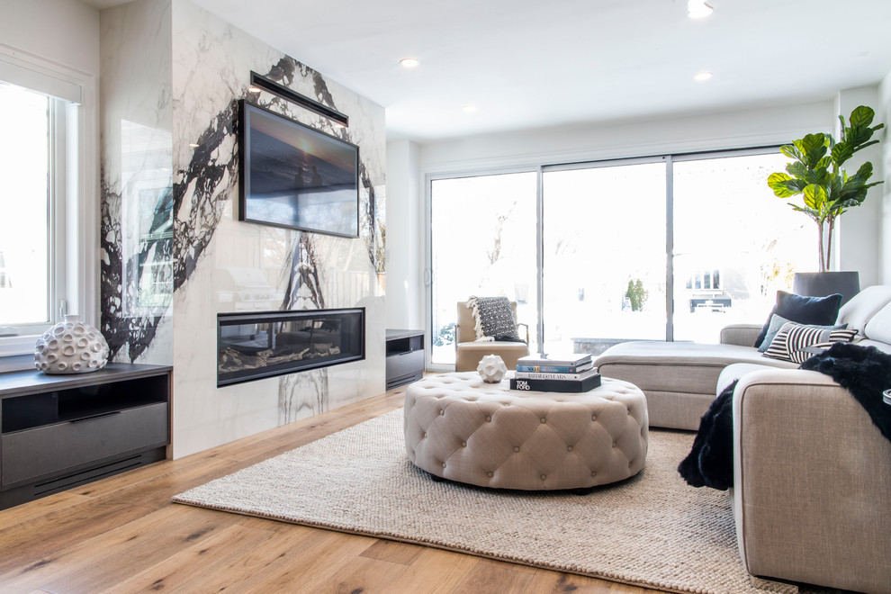 Foto de sala de estar abierta moderna de tamaño medio con paredes blancas, suelo de madera en tonos medios, chimenea lineal, marco de chimenea de piedra, televisor colgado en la pared, suelo marrón y alfombra