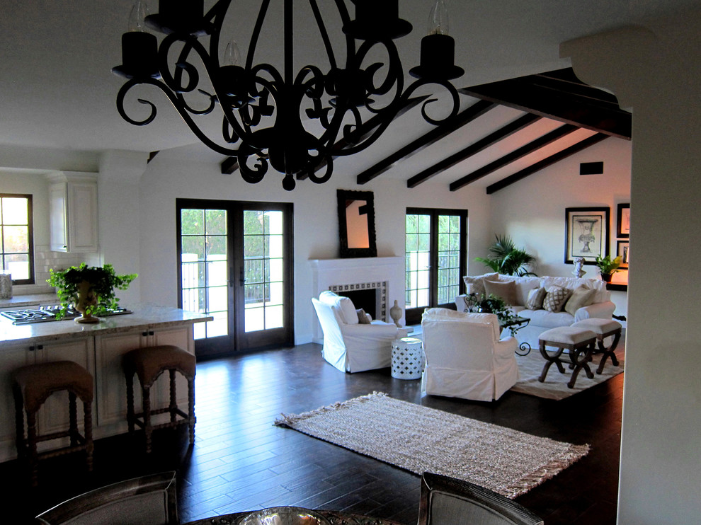 Пример оригинального дизайна: двухуровневая гостиная комната среднего размера в средиземноморском стиле с белыми стенами, темным паркетным полом, стандартным камином, фасадом камина из бетона и коричневым полом