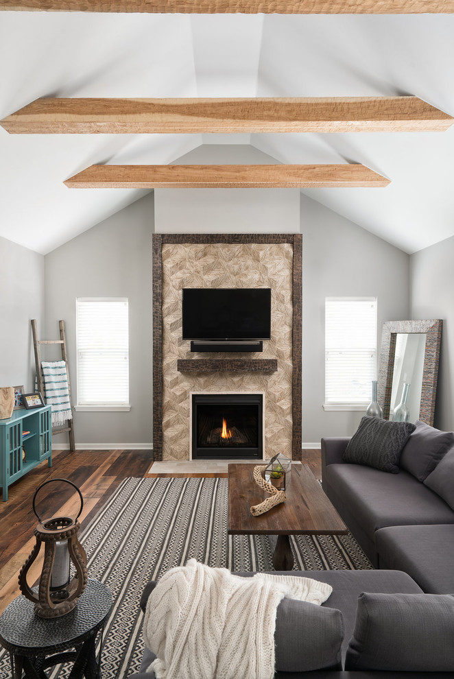 Aménagement d'une grande salle de séjour classique ouverte avec un mur gris, un sol en bois brun, une cheminée standard, un manteau de cheminée en carrelage, un téléviseur fixé au mur et un sol marron.