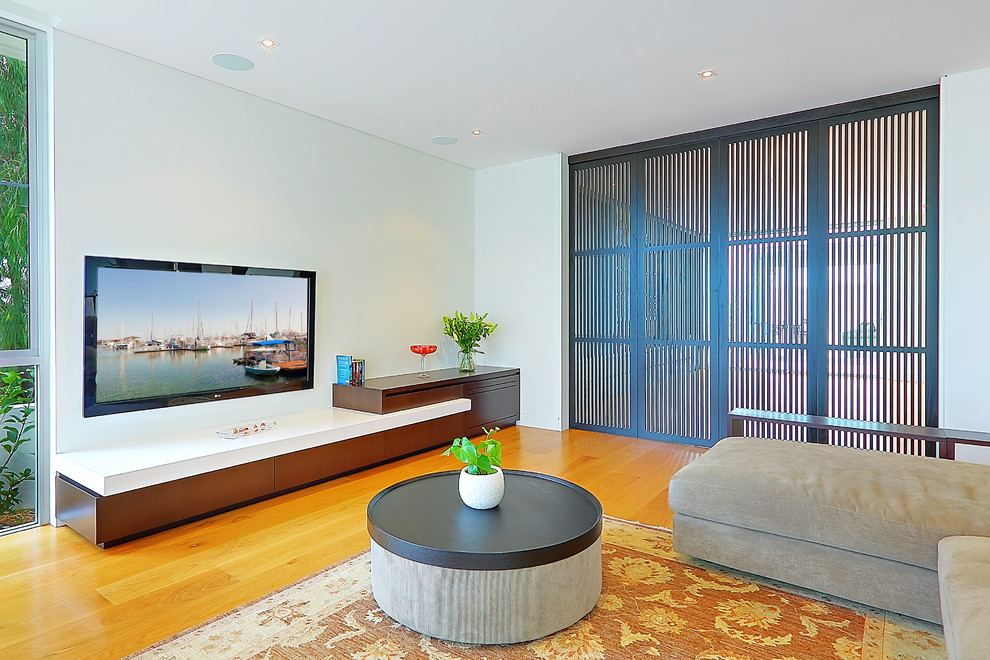 Источник вдохновения для домашнего уюта: открытая гостиная комната в современном стиле с белыми стенами, паркетным полом среднего тона и телевизором на стене