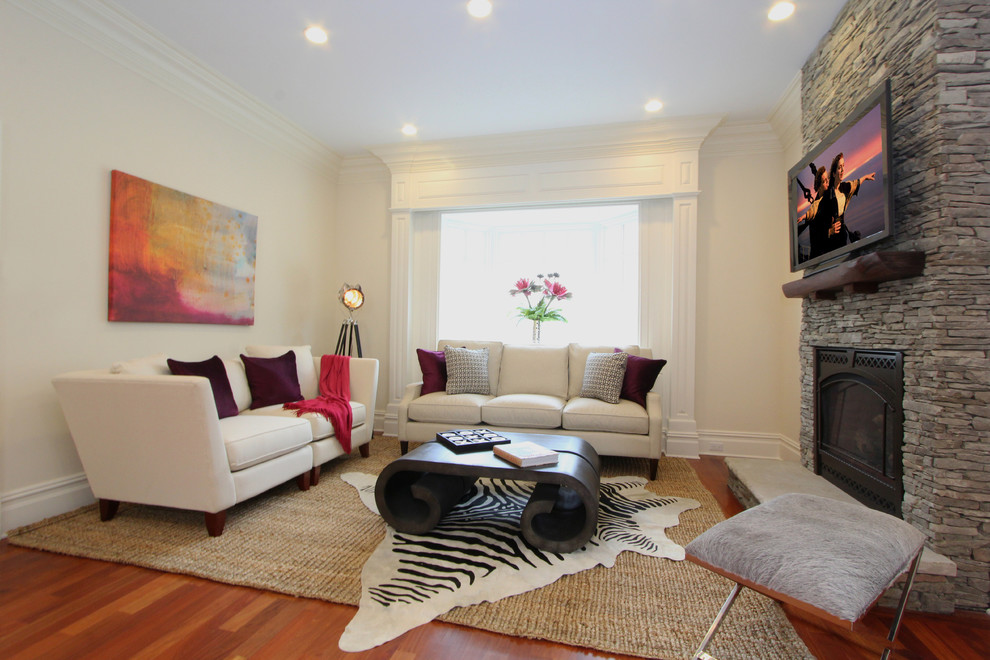 Modelo de sala de estar abierta minimalista de tamaño medio con paredes blancas, suelo de madera en tonos medios, todas las chimeneas, marco de chimenea de piedra y televisor colgado en la pared