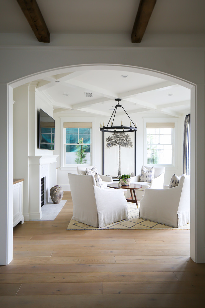 Immagine di un soggiorno costiero con pareti bianche, pavimento in legno massello medio, camino classico, TV a parete e pavimento marrone