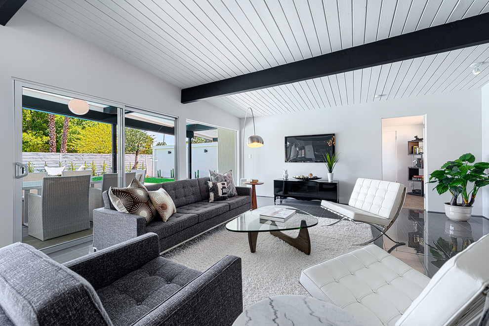 На фото: открытая гостиная комната в современном стиле с серыми стенами и телевизором на стене