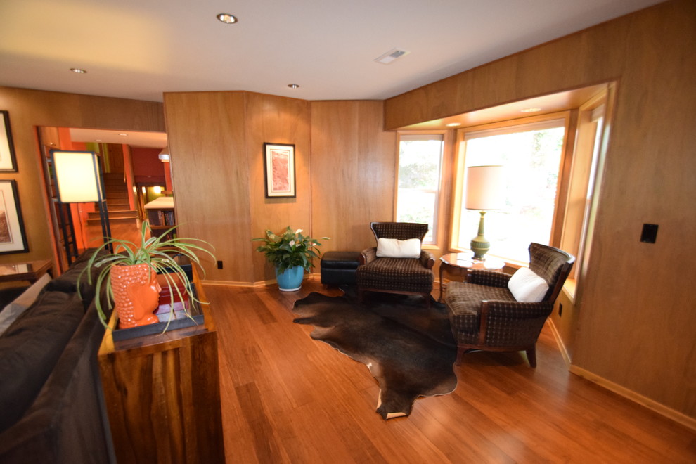 Immagine di un grande soggiorno moderno chiuso con pareti marroni, pavimento in bambù, stufa a legna, cornice del camino in pietra e pavimento marrone
