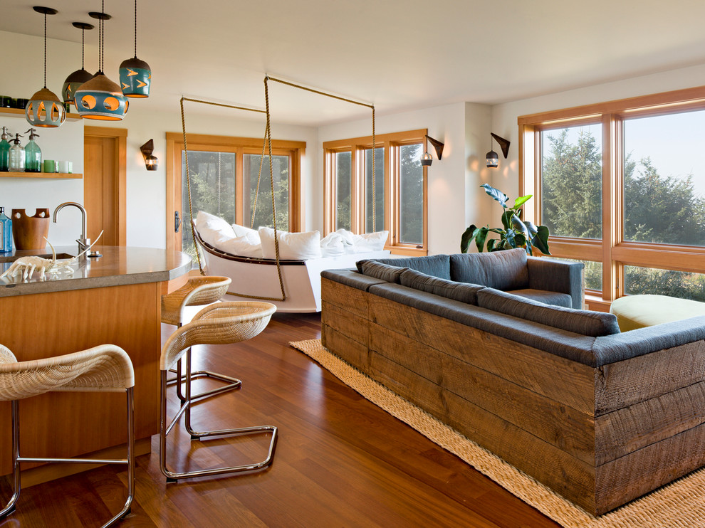 Exemple d'une salle de séjour bord de mer ouverte avec un mur beige et un sol en bois brun.