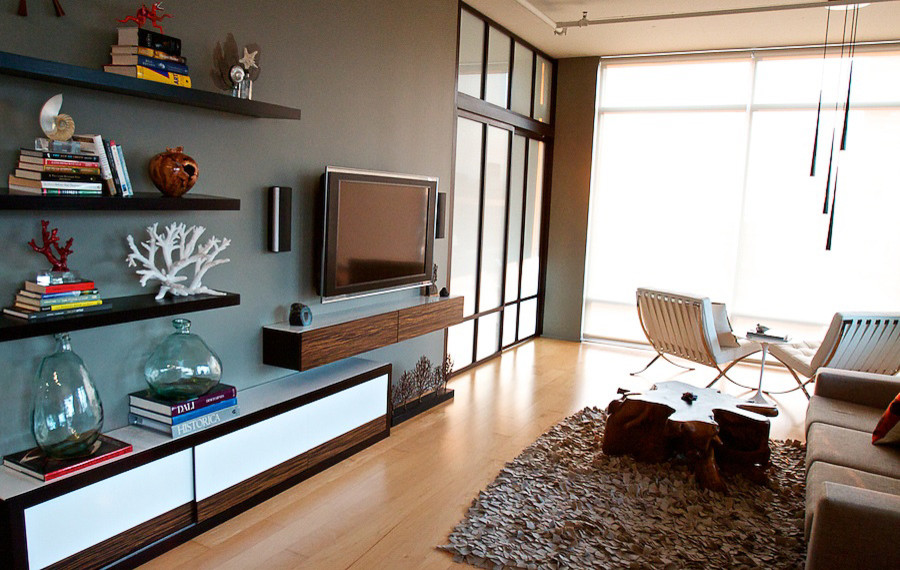 Diseño de sala de estar abierta actual grande con paredes azules, suelo de madera clara y televisor colgado en la pared