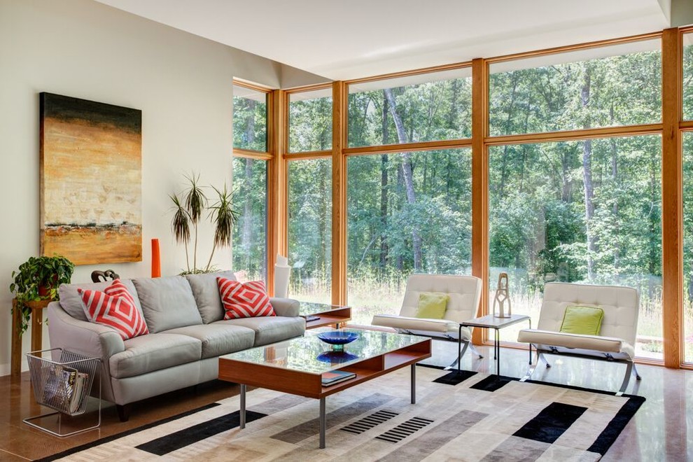 Diseño de sala de estar abierta contemporánea grande sin chimenea con televisor independiente, paredes grises, suelo de cemento, suelo marrón y alfombra