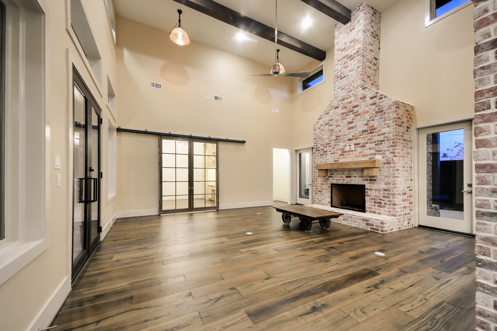 This is an example of an expansive classic open plan games room in Houston with a home bar, medium hardwood flooring, a standard fireplace, a brick fireplace surround, a wall mounted tv and beige walls.