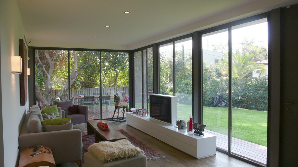 Exemple d'une salle de séjour tendance avec un mur beige, un sol en bois brun et un téléviseur indépendant.