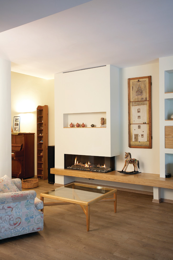 Aménagement d'une salle de séjour montagne avec un mur blanc, parquet clair, une cheminée ribbon et un manteau de cheminée en plâtre.