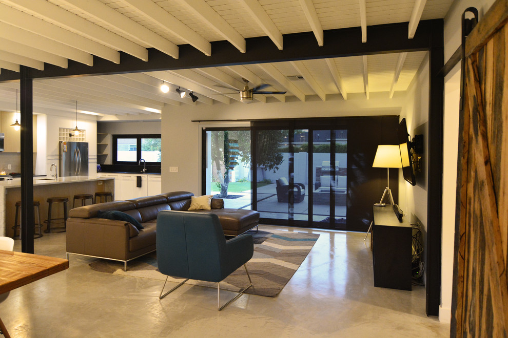 На фото: открытая гостиная комната среднего размера в стиле лофт с белыми стенами, бетонным полом и телевизором на стене без камина с