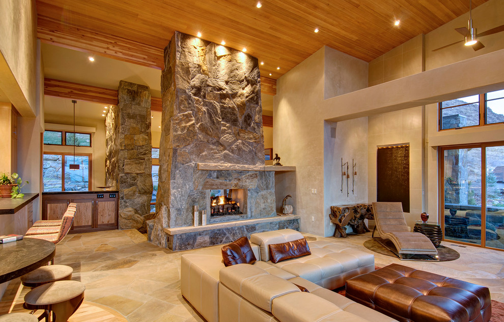Imagen de sala de estar abierta contemporánea grande sin televisor con marco de chimenea de piedra, paredes beige, suelo de travertino, chimenea de doble cara y suelo beige