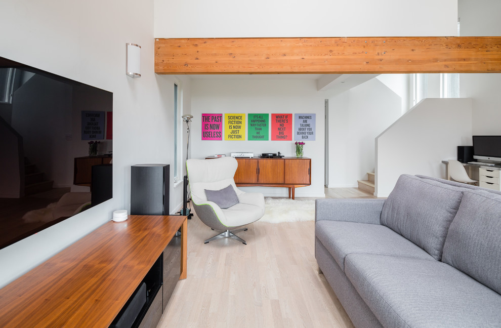 Bild på ett funkis allrum med öppen planlösning, med vita väggar, ljust trägolv, en väggmonterad TV och beiget golv