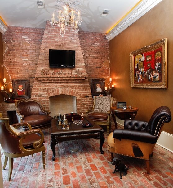 На фото: изолированная комната для игр среднего размера в классическом стиле с коричневыми стенами, кирпичным полом, стандартным камином, фасадом камина из кирпича и телевизором на стене с