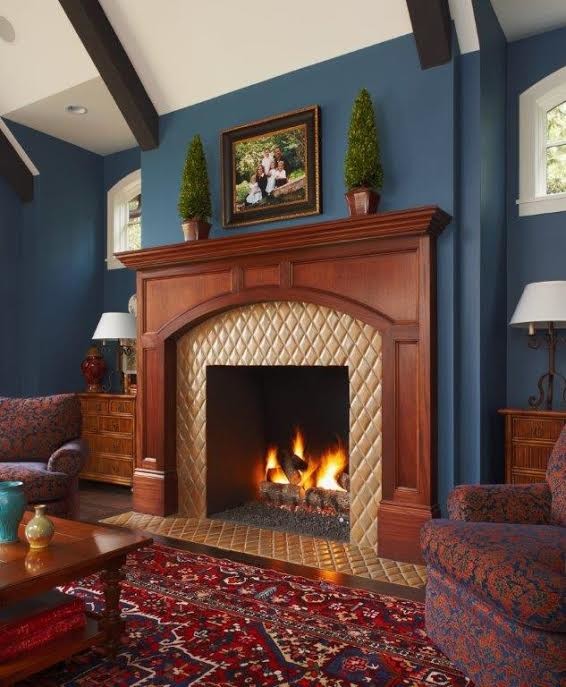 Cette image montre une salle de séjour traditionnelle de taille moyenne et fermée avec un mur bleu, une cheminée standard, parquet foncé, un manteau de cheminée en carrelage et aucun téléviseur.