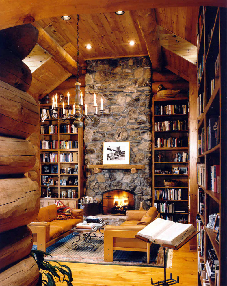 Diseño de sala de estar con biblioteca abierta de tamaño medio sin televisor con paredes beige, suelo de madera en tonos medios, todas las chimeneas y marco de chimenea de piedra