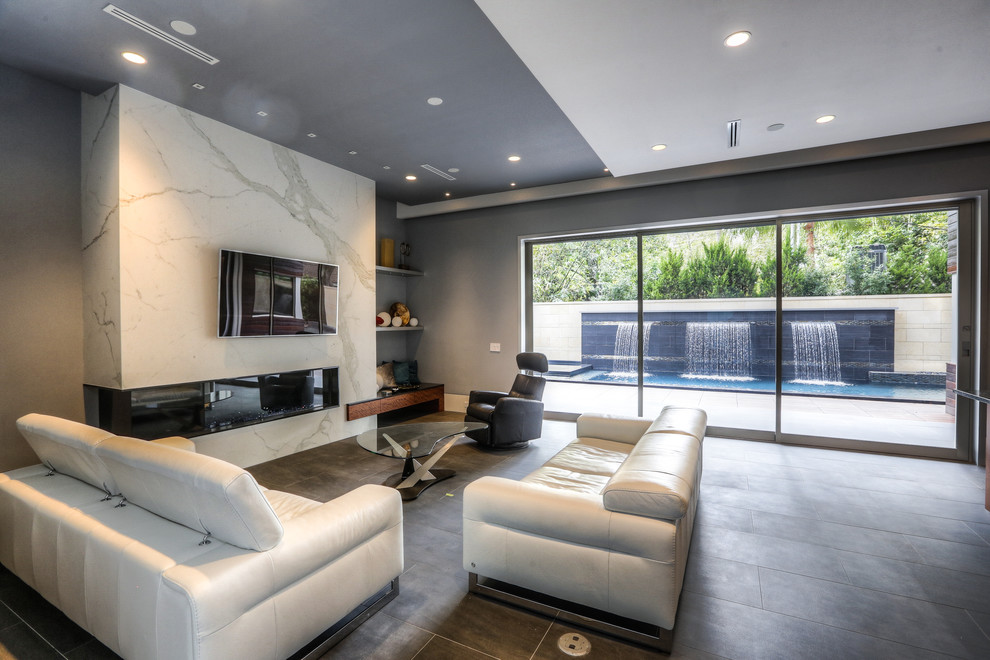 Пример оригинального дизайна: огромная открытая гостиная комната в стиле модернизм с серыми стенами, полом из сланца, горизонтальным камином, фасадом камина из плитки, телевизором на стене и серым полом