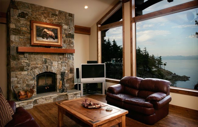 Mittelgroßes, Abgetrenntes Rustikales Wohnzimmer mit beiger Wandfarbe, hellem Holzboden, Kamin, Kaminumrandung aus Stein, Eck-TV und braunem Boden in Vancouver
