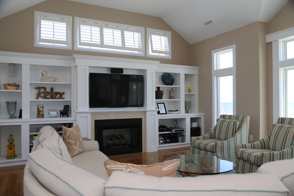 Idée de décoration pour une salle de séjour marine ouverte avec un mur beige, un sol en bois brun, une cheminée standard, un manteau de cheminée en carrelage et un téléviseur encastré.