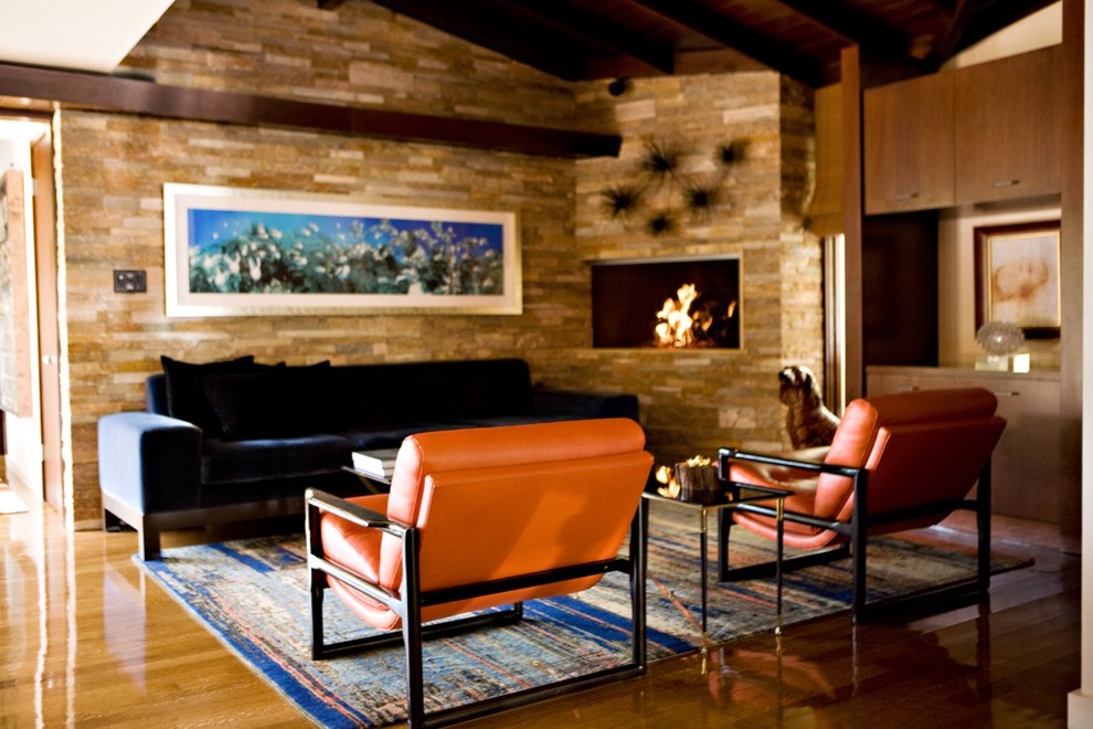 Ejemplo de sala de estar con barra de bar abierta vintage de tamaño medio sin televisor con suelo de madera en tonos medios, marco de chimenea de piedra, paredes beige, chimenea lineal y suelo marrón