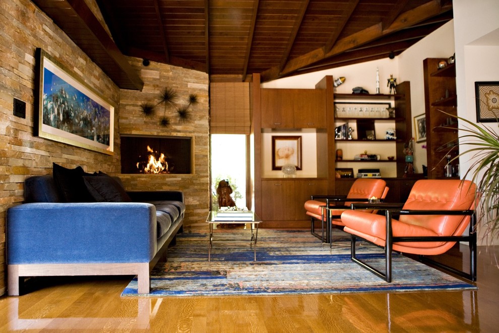 Inspiration for a mid-sized mid-century modern open concept medium tone wood floor and brown floor family room remodel in Los Angeles with a stone fireplace, a bar, beige walls, a ribbon fireplace and no tv